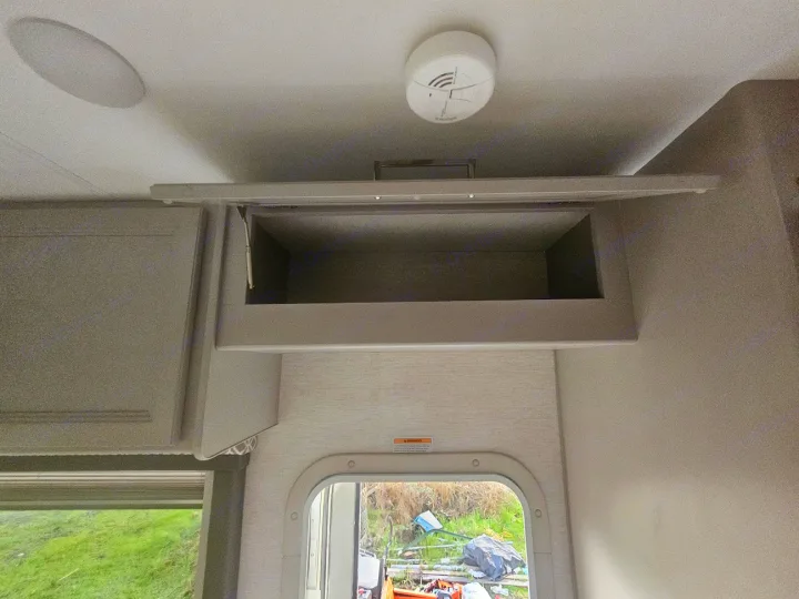 RV rental interior showing open overhead cabinet, smoke detector, and ceiling speaker. Good storage options.. Thor Coleman 28AMC 2024