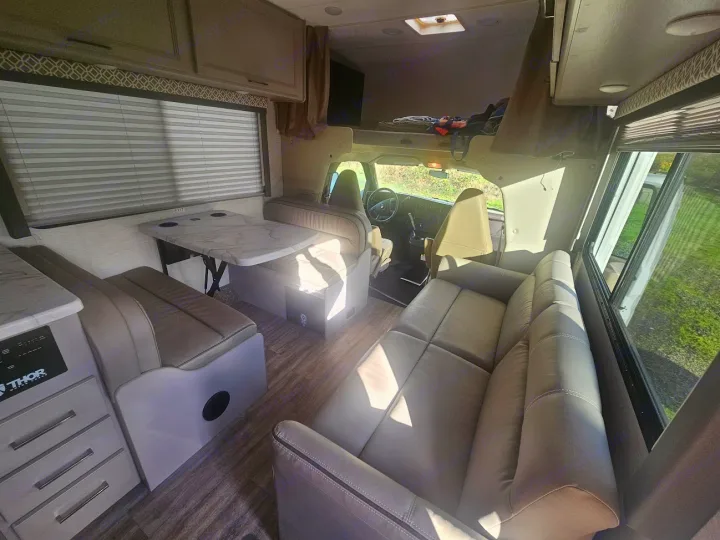 Spacious and modern rv rental interior with bright living area, dinette, sofa, and bunk. Ready for your next adventure!. Thor Coleman 28AMC 2024