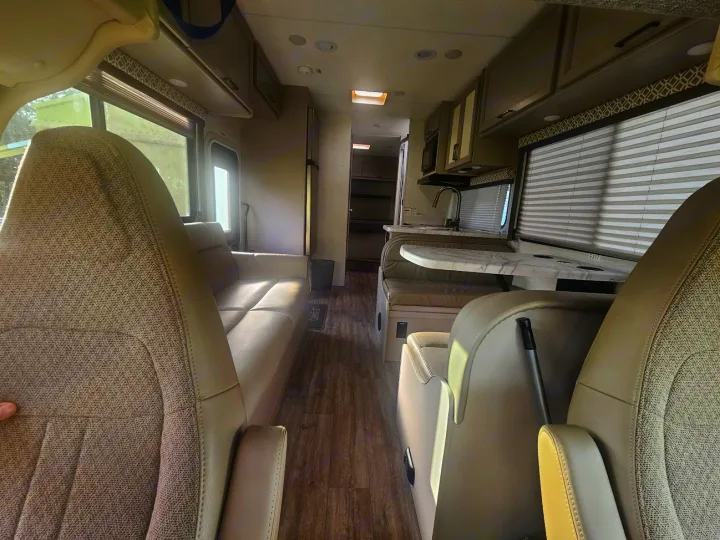 Spacious RV rental interior from front, showing sofa, dinette, and kitchen area. Light, inviting living space.. Thor Coleman 28AMC 2024