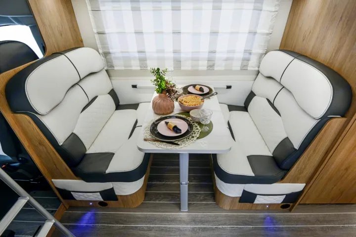 Comfortable RV rental interior: A modern dinette with black & white seating, set for a cozy meal, perfect for travel.. Roller Team Auto-Roller 746 2025