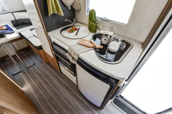 Bright RV rental interior features a compact kitchen with a sink, counter, small appliances, and a cozy dining area.. Roller Team Auto-Roller 746 2025