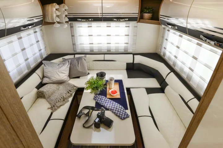 Spacious, modern RV rental interior featuring a U-shaped black and white leatherette lounge, central table, and overhead storage. Ideal for comfortable travel.. Roller Team Auto-Roller 746 2025