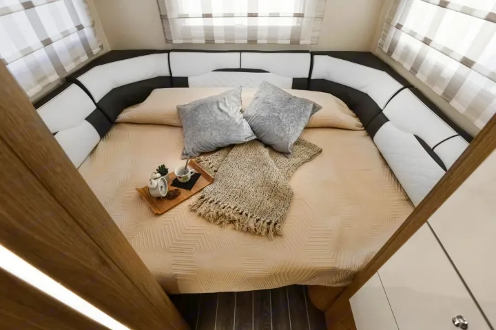 Inside a premium rv rental: a welcoming bedroom with a large bed, wrap-around seating, and a thoughtful breakfast setup.. Roller Team Auto-Roller 746 2025