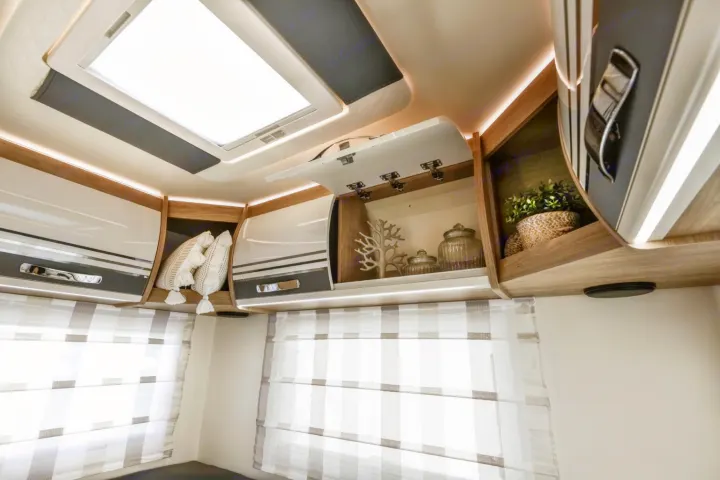 Inside an RV rental: bright overhead storage with decorative items, ambient lights, large skylight, and striped blinds.. Roller Team Auto-Roller 746 2025