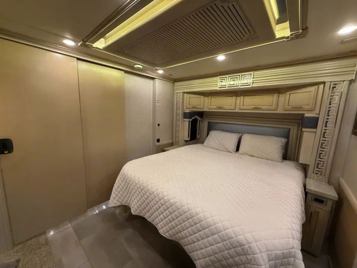 Explore this modern RV rental bedroom: large bed with quilted cover, ample overhead storage, and bright ambient lighting.. Newmar Ventana 2020