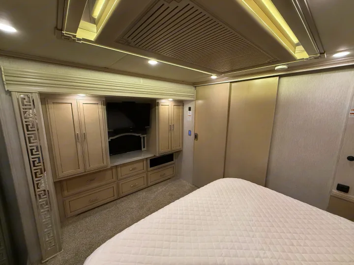 RV rental bedroom featuring a comfortable bed, built-in cabinetry, and TV. A cozy interior for your journey.. Newmar Ventana 2020