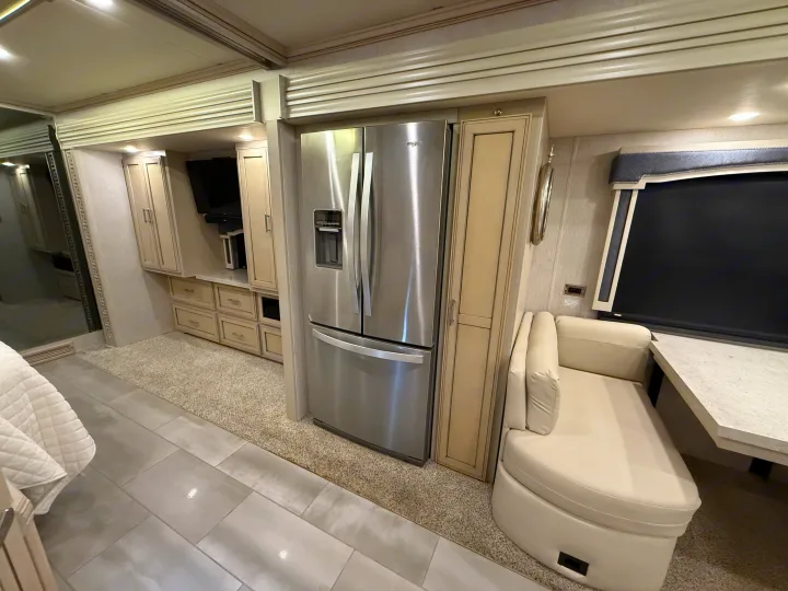 Modern motorhome RV rental interior: full-size fridge, sleek cream cabinetry, comfy lounge, and mixed flooring.. Newmar Ventana 2020