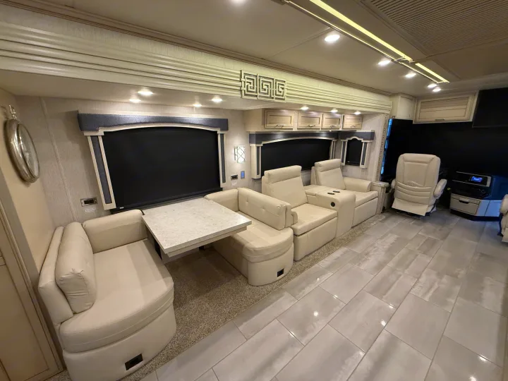 Spacious, luxurious RV rental interior featuring cream leather seating, a dining area, and sleek tiled flooring.. Newmar Ventana 2020