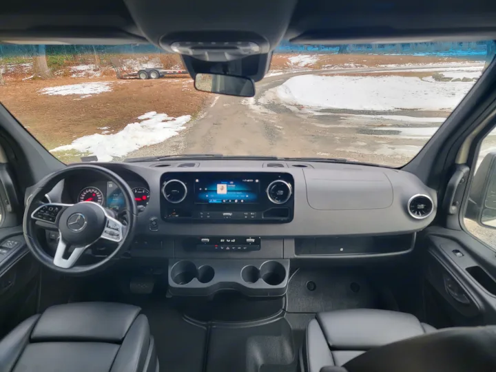 RV rental: Inside a Mercedes-Benz Sprinter camper van, showing the dashboard, steering wheel, and snowy road.. Mercedes-Benz Sprinter 2022