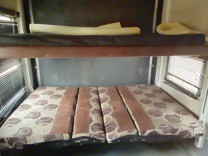 RV rental: Versatile interior with lower convertible bed (patterned cushions) and upper bunk for flexible sleeping.. Keystone Fuzion 2015