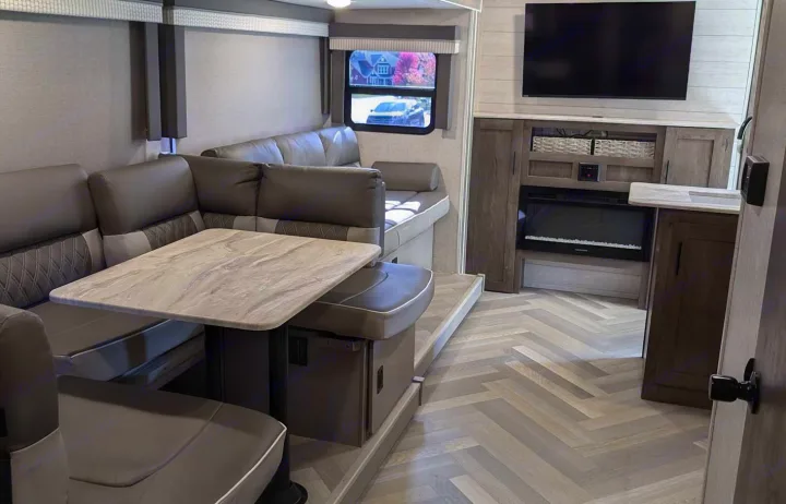 Modern RV rental living space with a comfy dinette, TV, fireplace, and stylish herringbone floor. Perfect for your next adventure!. Forest River Salem Cruise Lite 2021
