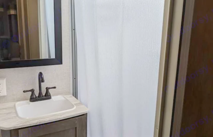 Compact RV rental bathroom featuring a sink, mirror, and white textured shower door.. Forest River Salem Cruise Lite 2021