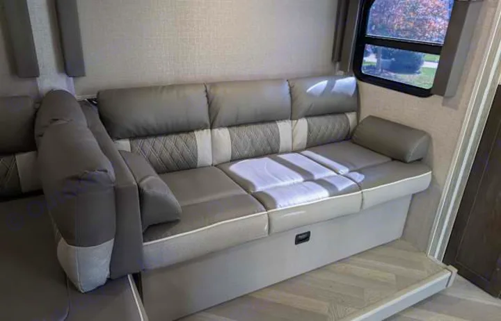 This RV rental offers a modern gray L-shaped sofa with a window, providing comfortable seating and a relaxing space.. Forest River Salem Cruise Lite 2021