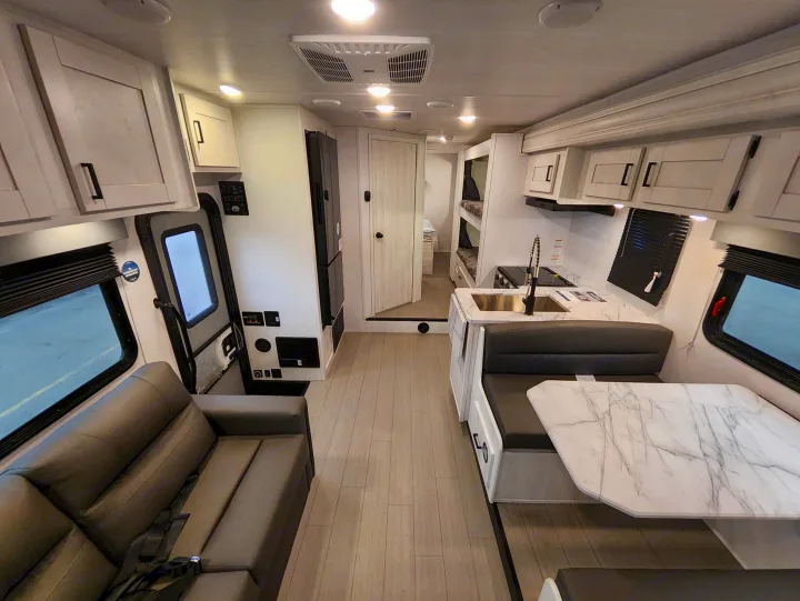 Inside a spacious rv rental, featuring a living room with sofa, kitchen, dining area, and bunk beds.. East To West Entrada 2025