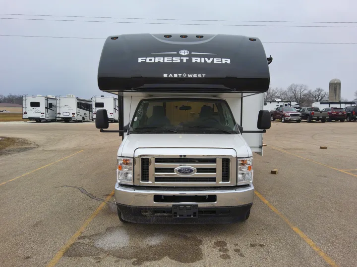Front view of a white Forest River Class C RV for RV rental, parked on asphalt. Other campers visible in the background.. East To West Entrada 2025