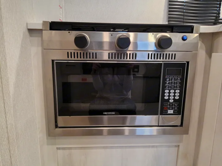 Compact Greystone microwave oven & cooktop in an rv rental, featuring convection, grill, and stove functions for versatile cooking.. East To West Entrada 2025
