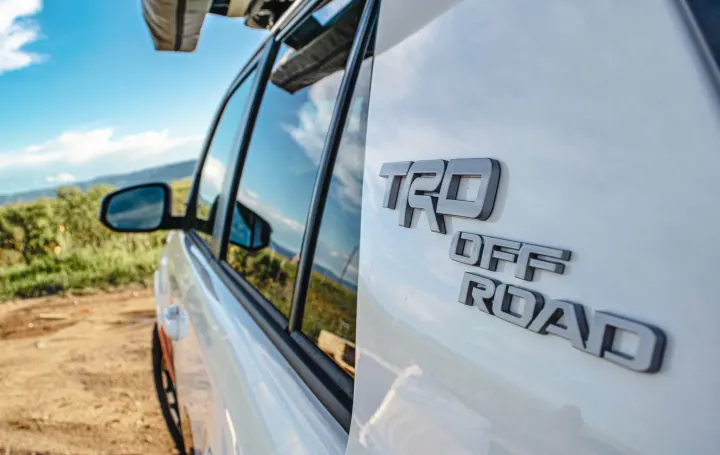White TRD Off Road SUV with rooftop tent on dirt road, perfect for RV rental adventures.. Toyota 4Runner 2024