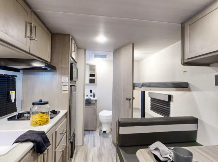 Explore this RV rental's versatile interior: full kitchen, compact bathroom, comfy bunk beds & dinette.. Keystone RV Springdale 2024