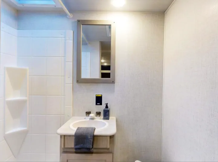Modern RV rental bathroom: vanity with sink, mirror, and bright shower with skylight, designed for comfortable travel.. Keystone RV Springdale 2024