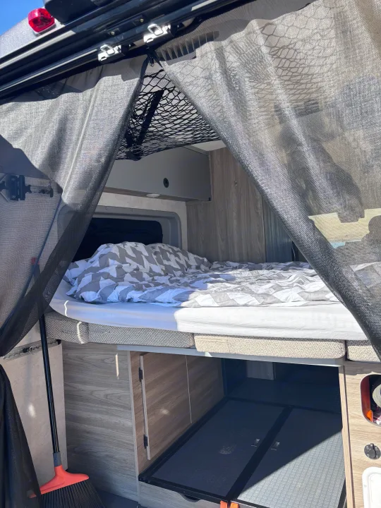 RV rental interior featuring a comfortable bed, overhead storage net, under-bed storage, and a protective bug screen.. Winnebago Winnebago 2024
