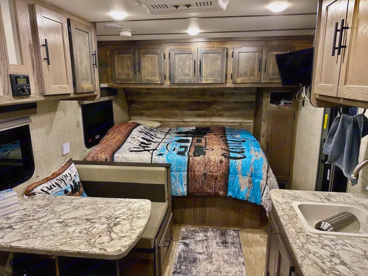 Modern RV rental interior: rustic wood accents, comfy bed, dinette, and kitchen for your next adventure.. Gulf Stream Ameri-Lite Super Lite 2021