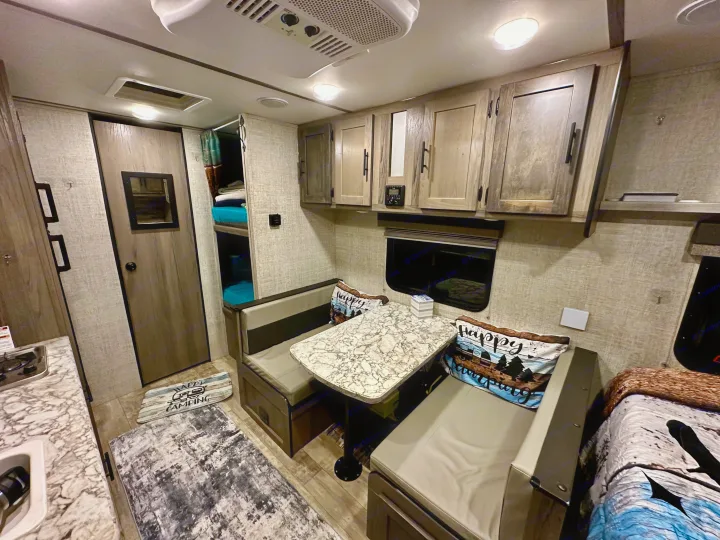 Inside this **rv rental**: a comfy dinette, compact kitchen, and convenient bunk beds, ideal for your next road trip.. Gulf Stream Ameri-Lite Super Lite 2021