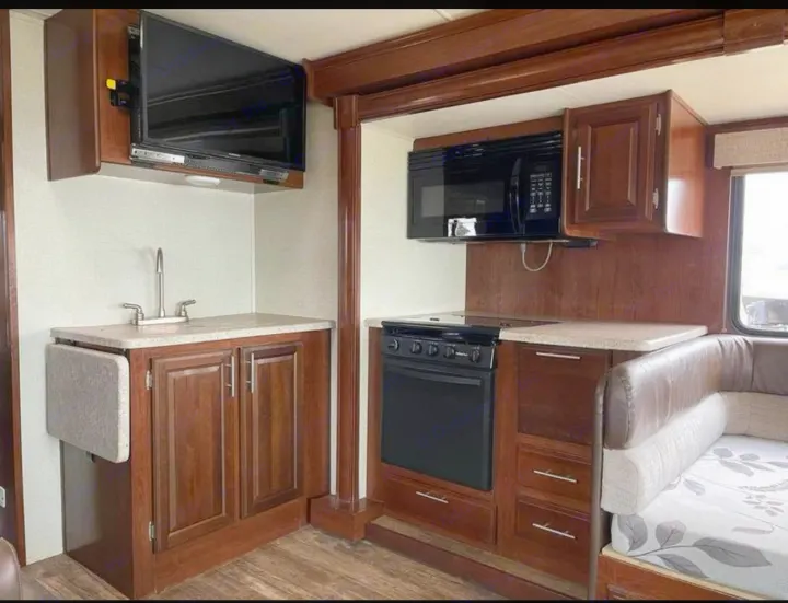 Well-equipped RV rental kitchen and living area, featuring a TV, microwave, oven, sink, and comfortable dinette.. FR3 FR3 Motorhome 2017