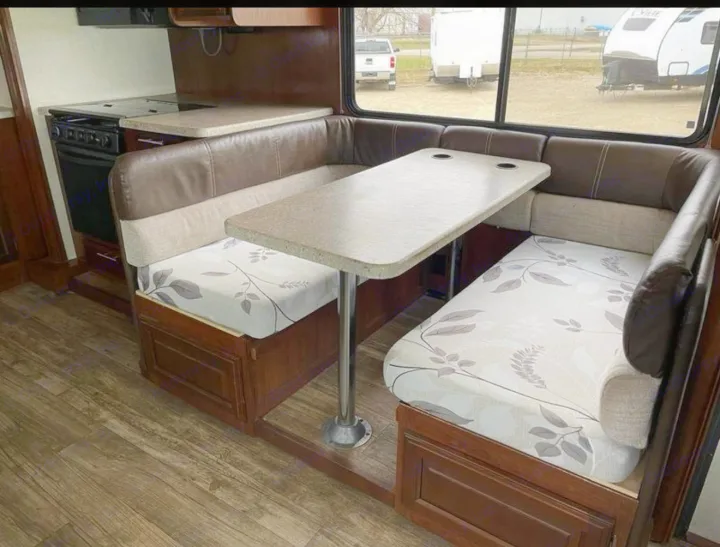 Inside an RV rental: U-shaped dinette with patterned cushions, central table, and adjacent kitchen. Ideal for your next trip.. FR3 FR3 Motorhome 2017
