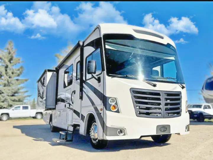 Large white & gray Class A motorhome for rv rental, parked outdoors. Slide-outs extended, steps down. Sunny day, blue sky.. FR3 FR3 Motorhome 2017