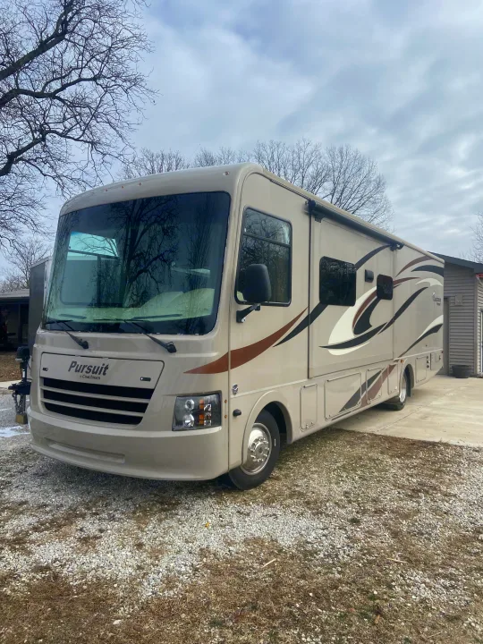 A large, tan Coachmen Pursuit motorhome parked on a gravel driveway, ready for rv rental.. Forest River Coachmen Pursuit 2017