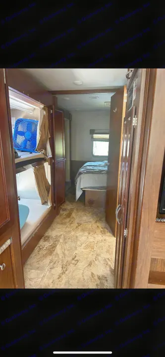 This RV rental's interior shows bunk beds with a blue fan on the left, leading to the bedroom on the right. A functional mobile living space.. Forest River Coachmen Pursuit 2017