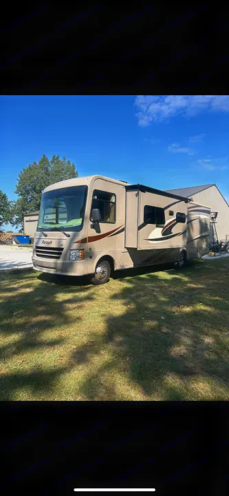 Light-colored Pursuit Class A RV rental parked on green grass. Ideal for your next outdoor adventure under a sunny sky.. Forest River Coachmen Pursuit 2017