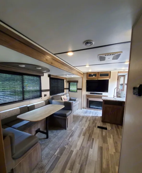 Stylish RV rental interior with a spacious dinette, living area featuring TV/fireplace, and a functional kitchen.. Crossroads RV Zinger 2021