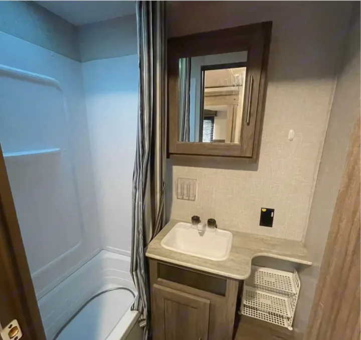 RV rental bathroom features: compact tub/shower, sink vanity, and mirrored cabinet. A practical interior for your journey.. Crossroads RV Zinger 2021