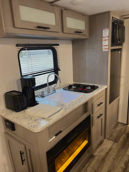 RV rental: Modern, compact kitchen featuring sink, stove, microwave, fridge, toaster, coffee maker, and fireplace.. Dutchmen Coleman Lantern LT 17B 2024