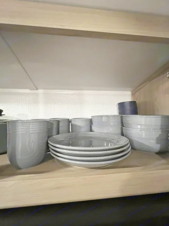Kitchenware in an RV rental: gray plates, bowls, & cups neatly stored in the cabinet for your trip.. Forest River Rockwood Geo Pro 2024