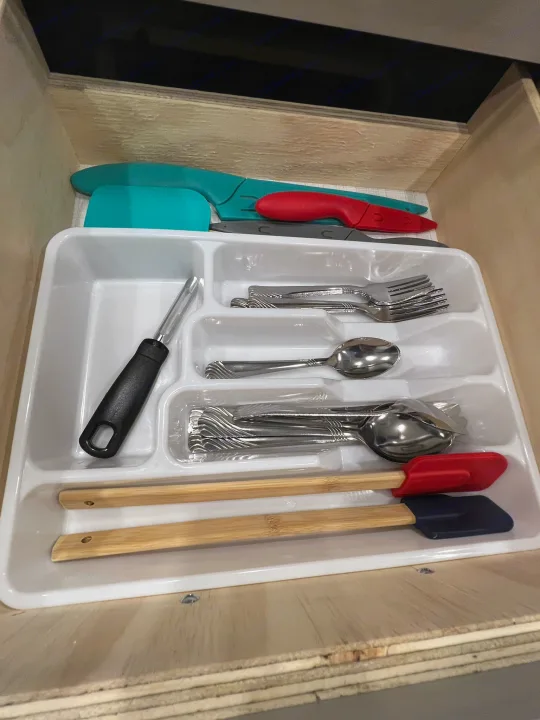 Organized RV rental kitchen drawer with forks, spoons, spatulas, and knives in a white tray.. Forest River Rockwood Geo Pro 2024