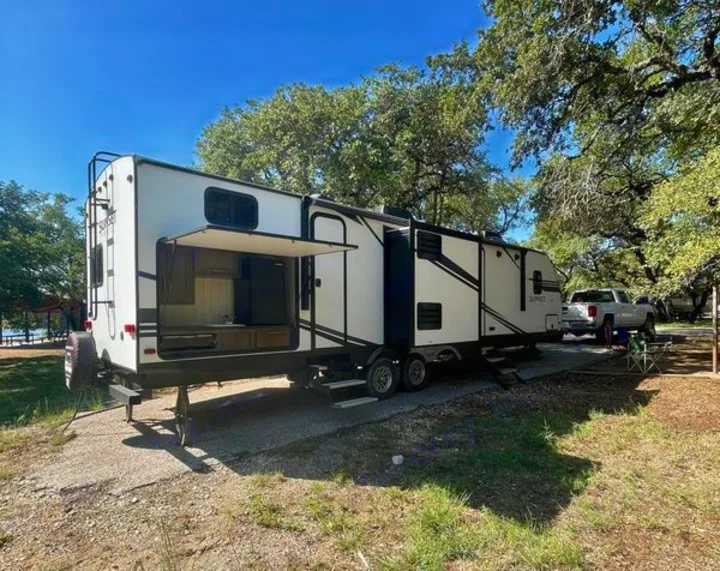 Enjoy your **rv rental** with this spacious travel trailer, featuring an outdoor kitchen at a beautiful lakeside campsite.. Crossroads RV Sunset Trail Super Lite 2019