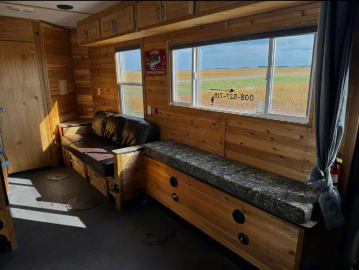 Cozy wood-paneled ice fishing house interior for rv rental, featuring seating, cabinets, and floor fishing access.. Ice Castle Fish Houses Toy Hauler 2019