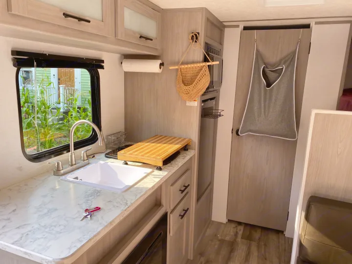 Step into this bright RV rental's modern kitchen, featuring a white sink, marble-look counter, and essential appliances.. Coleman Lantern 17B 2024