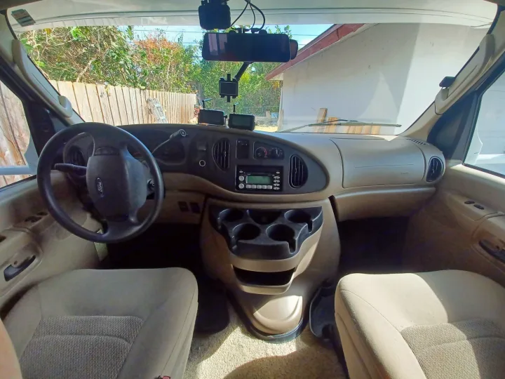 RV rental interior: driver's view of a van cab, showing dashboard, steering wheel, and front seats.. Winnebago Outlook 2007