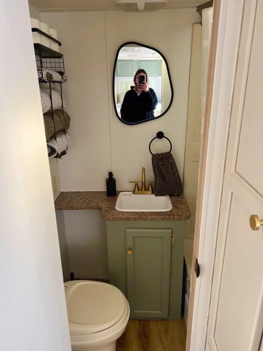 Modern RV rental bathroom featuring a sink, green vanity, mirror, toilet, and towel storage rack.. Aljo Aljo Trailer 2008