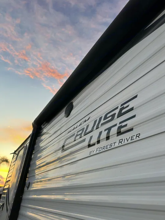 A white Salem Cruise Lite RV rental, with its branding visible, sits outdoors against a beautiful sunset sky.. Forest River Salem Cruise Lite 2019