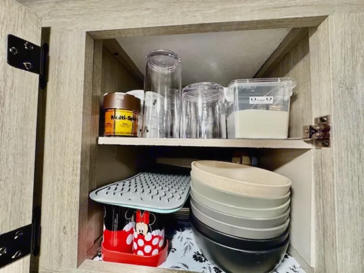 RV rental kitchen cabinet with neatly stacked bowls, glasses, and essentials, maximizing camper space.. Forest river Aurora 2025