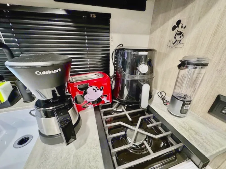 Explore a well-equipped RV rental kitchen: Cuisinart coffee maker, Mickey toaster, air fryer, Ninja blender & stovetop.. Forest river Aurora 2025