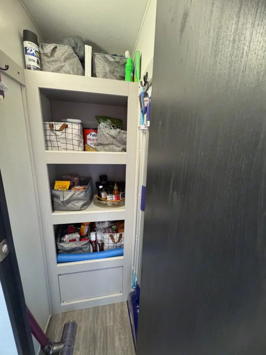 Organized RV rental pantry shelves with travel essentials like food, spices, and cleaning items, maximizing compact storage.. Heartland RVs Mallard 2024