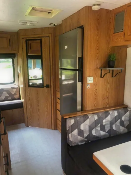 This RV rental interior features a spacious living area with a large stainless steel fridge, wood-paneled walls, and cozy dinette seating.. Ford Ford E350 1996