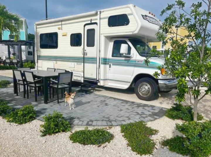 This inviting RV rental features a Class C RV on a paved patio with dining set and a small dog, perfect for a relaxing vacation.. Ford Ford E350 1996