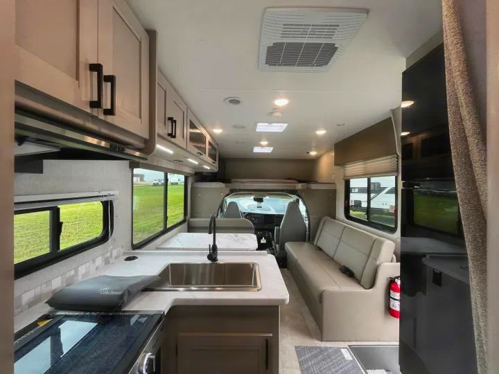 Inside a modern rv rental with a bright kitchenette, cozy seating, and cab-over bunk, perfect for road trips.. Forest River Coachmen Freelander 2026