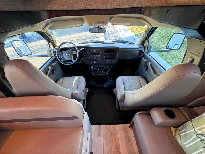 From the rear living area, an rv rental's front cabin shows the dashboard, steering wheel, and front seats.. Forest River Coachmen Freelander 2026
